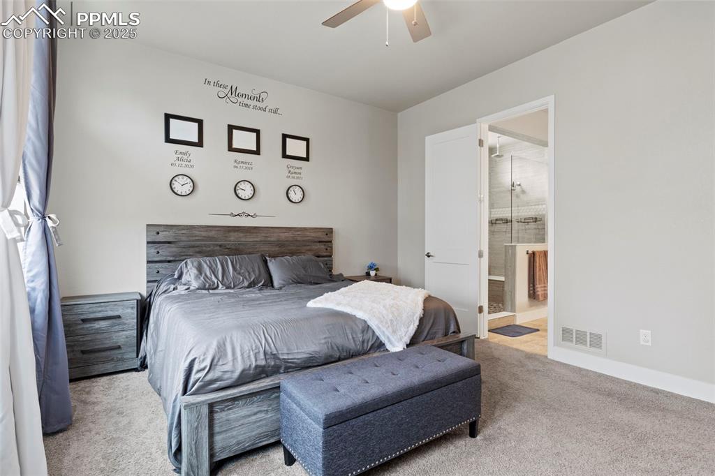 Image 13 of 38: Carpeted bedroom featuring ceiling fan and ensuite bath