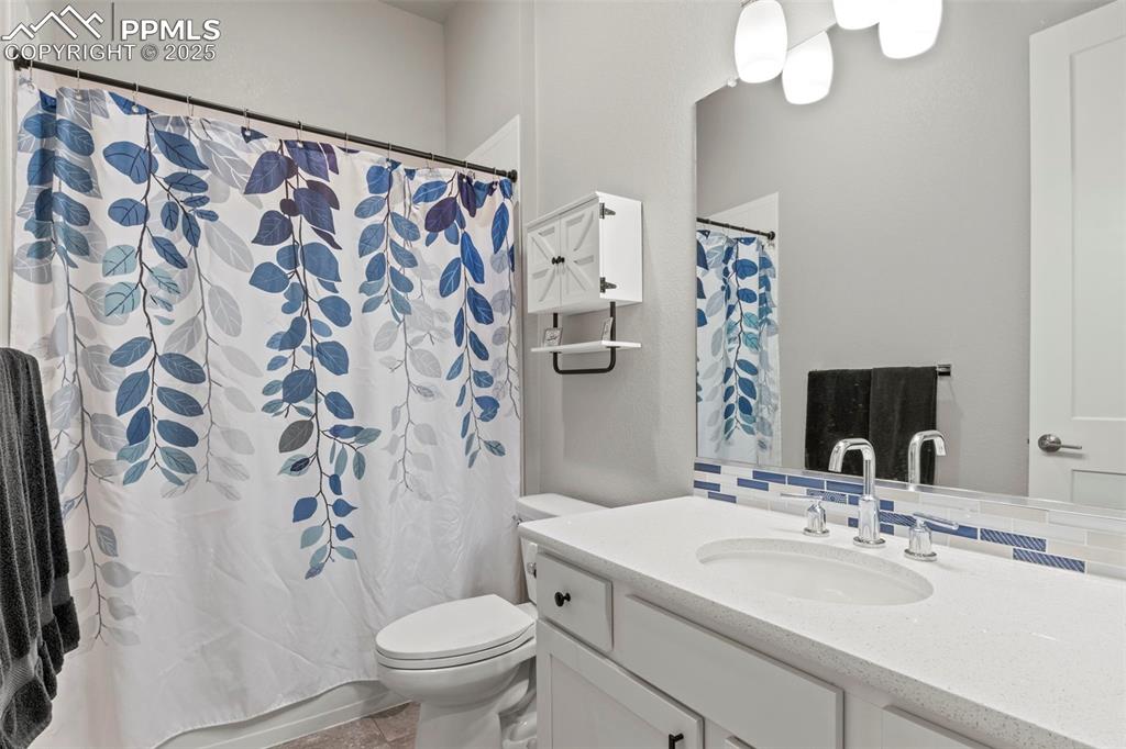 Image 26 of 38: Full bathroom featuring vanity, toilet, decorative backsplash, and curtaine