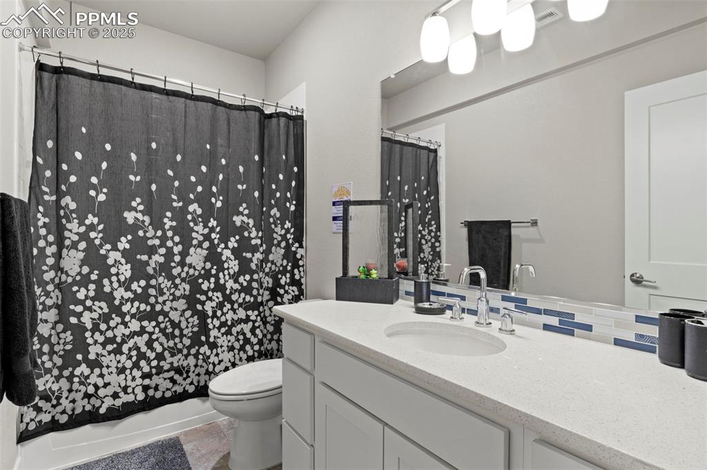 Image 32 of 38: Bathroom featuring decorative backsplash, a shower with curtain, toilet, va