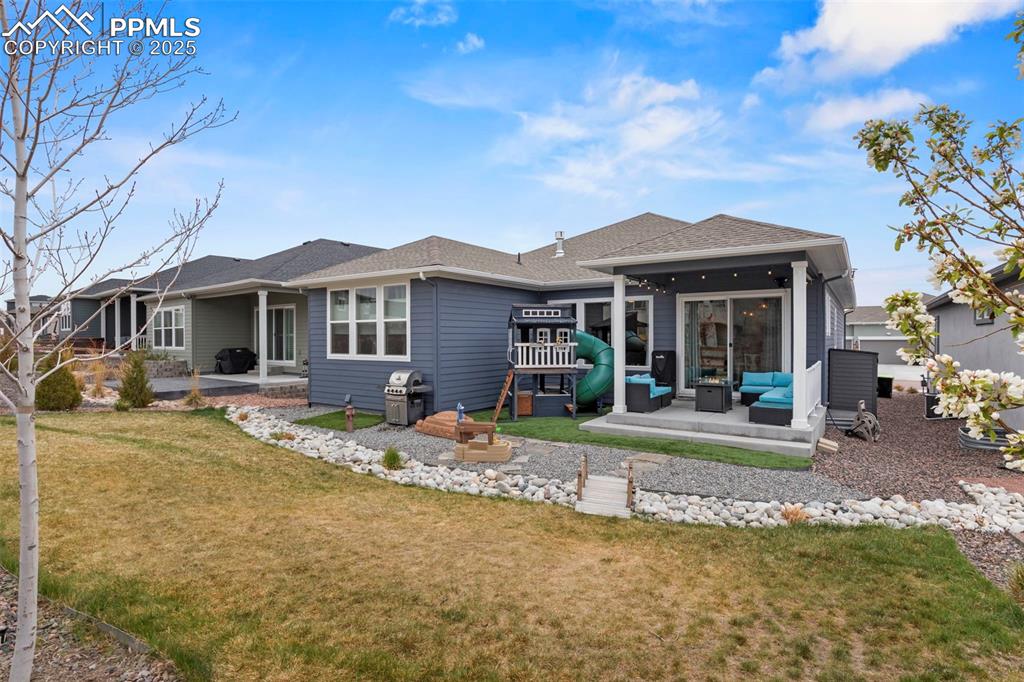 Image 38 of 38: Rear view of property featuring a lawn, an outdoor living space, a shingled