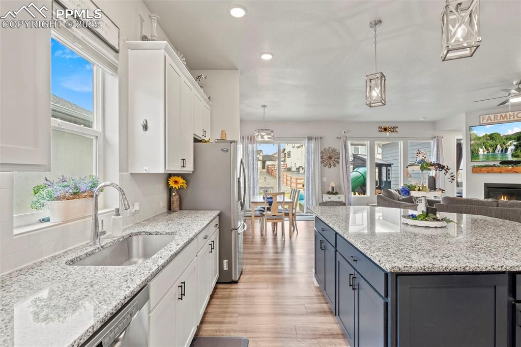 Image 4 of 38: Kitchen featuring white cabinets, open floor plan, light wood-style floorin