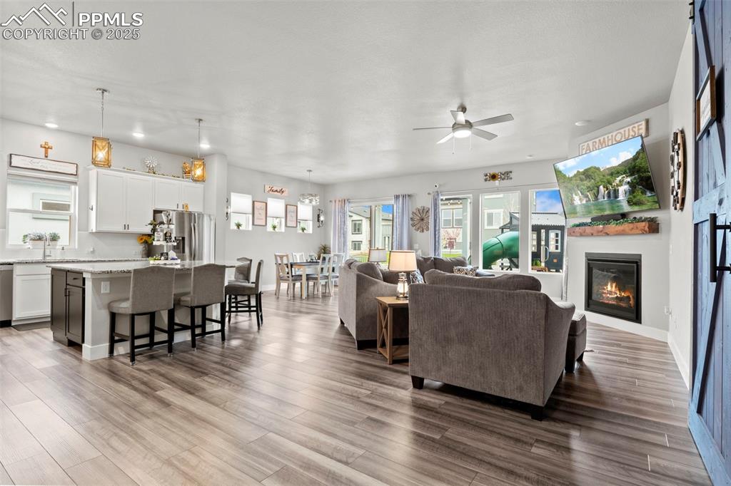 Image 6 of 38: Living room with dark wood finished floors, recessed lighting, ceiling fan,