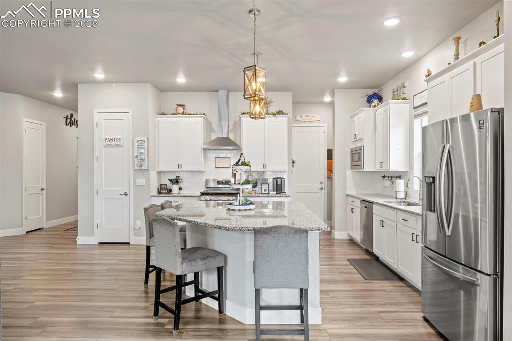 Image 9 of 38: Kitchen with a sink, light wood-type flooring, backsplash, wall chimney ran