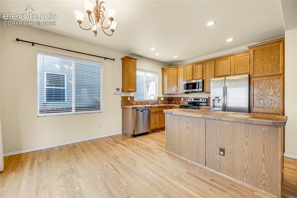 Image 10 of 39: Wood-finish flooring throughout, complemented by a kitchen island with a ti