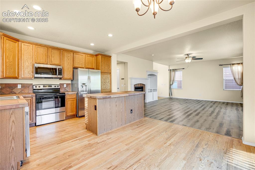 Image 11 of 39: Kitchen with wood-finish cabinetry, stainless steel appliances, and a centr