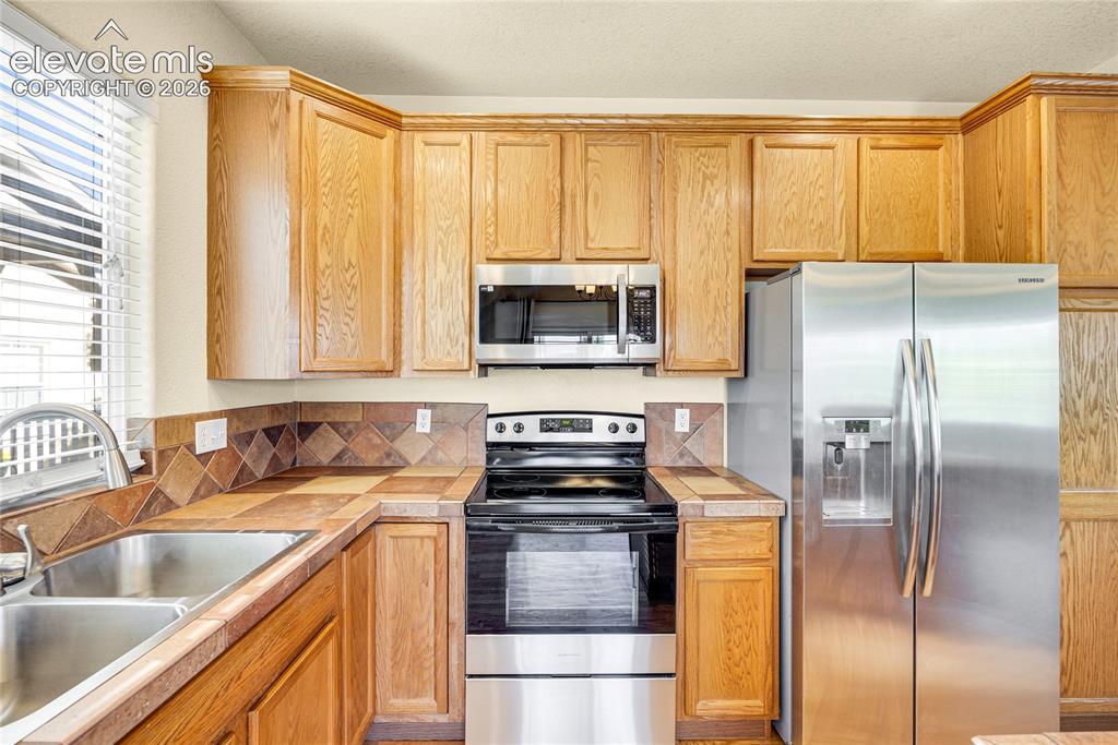 Image 12 of 39: Kitchen featuring wood cabinetry with crown molding, stainless steel applia