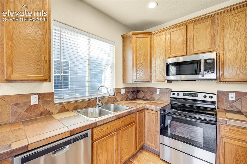 Image 13 of 39: Kitchen featuring wood cabinetry, stainless steel appliances, a double basi