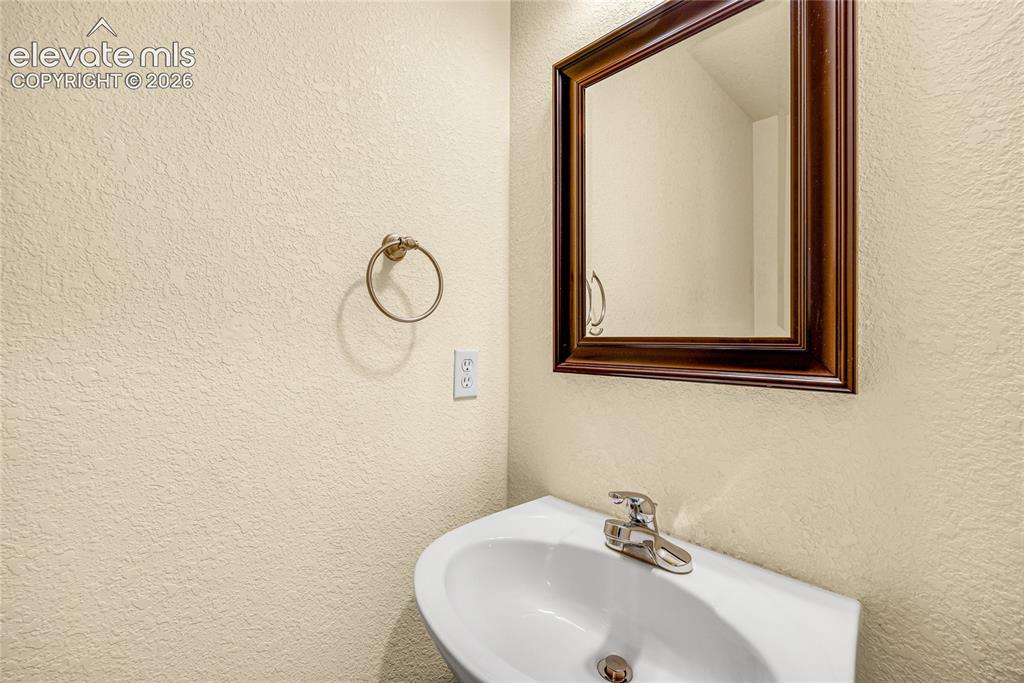 Image 15 of 39: Pedestal sink with a polished chrome faucet, framed mirror, and textured wa