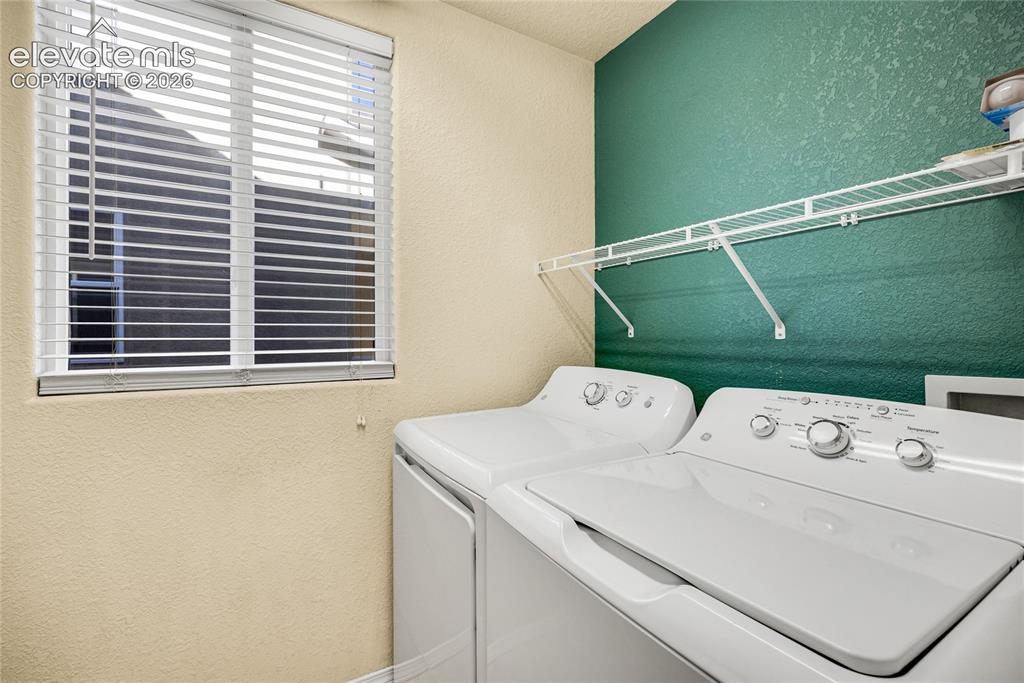 Image 16 of 39: Laundry area featuring a window with horizontal blinds, a wire shelving uni