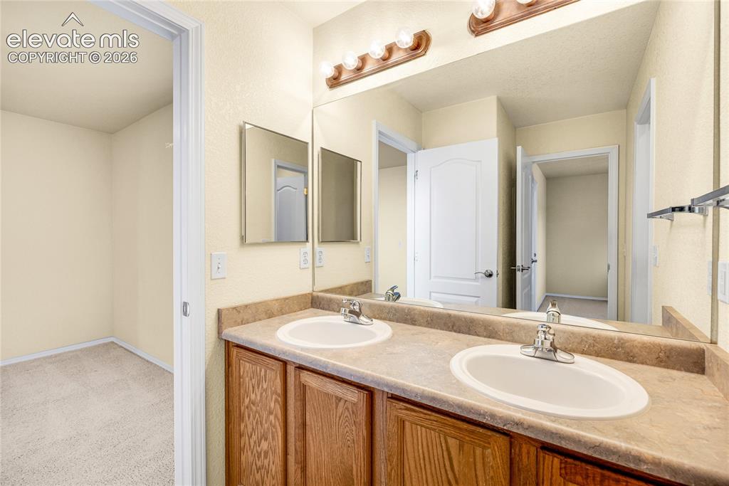 Image 23 of 39: Bathroom featuring a dual vanity with laminate countertops and wood-finish 