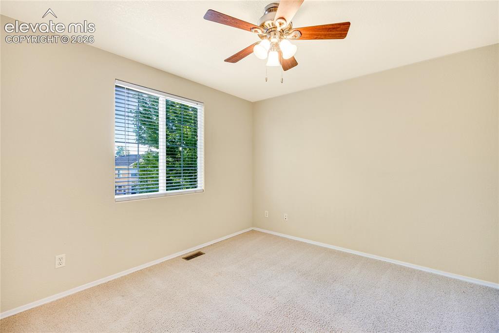 Image 24 of 39: Carpeted room with a ceiling fan light fixture, a window with horizontal bl