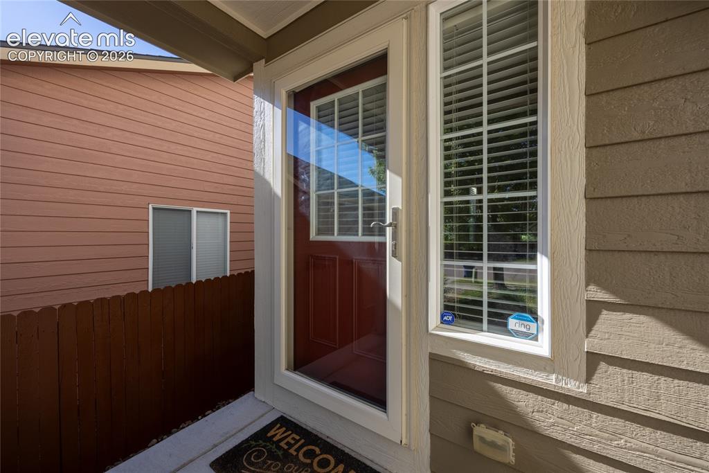 Image 3 of 39: Entryway featuring a red paneled door with a storm door, an adjacent sideli