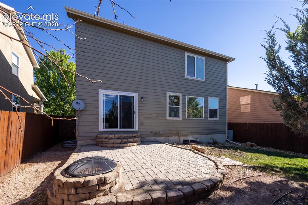 Image 30 of 39: Exterior rear featuring a paver patio with a built-in fire pit, gray horizo