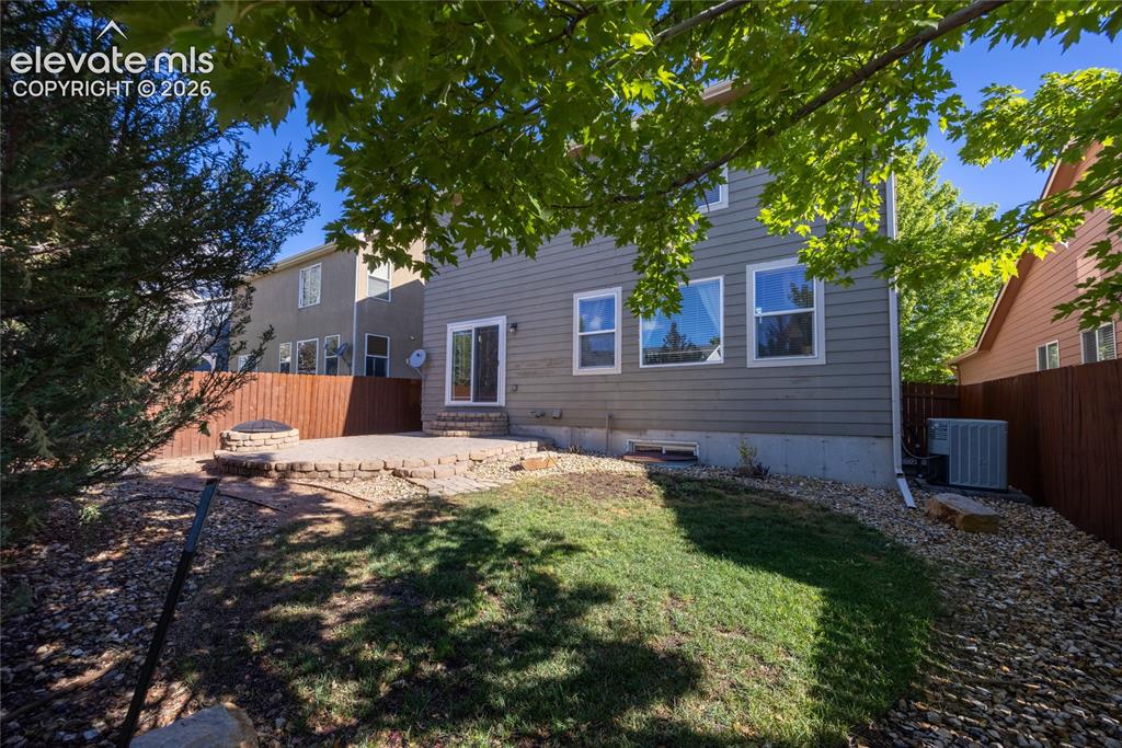Image 31 of 39: Backyard patio featuring a built-in fire pit, stone retaining wall, and sli