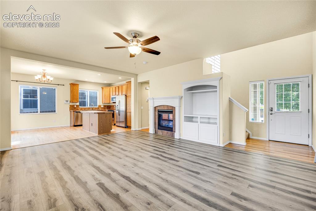 Image 8 of 39: Spacious living area featuring wood-finish flooring, a ceiling fan, and a f
