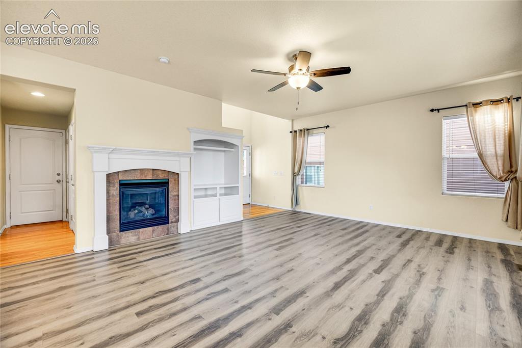 Image 9 of 39: Spacious living area featuring wood-finish flooring, a ceiling fan with int