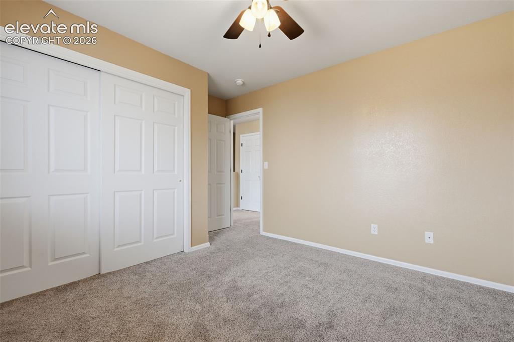 Image 11 of 21: Neutral tone wall paint, paneled interior doors, and a ceiling fan with lig