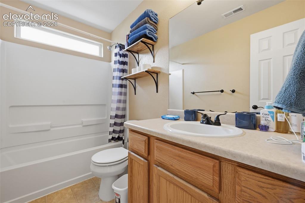 Image 13 of 21: Bathroom featuring a white bathtub, toilet, wood-finish vanity with an inte