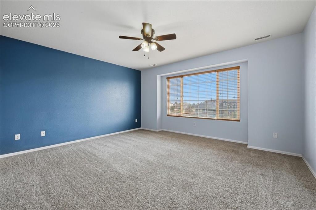 Image 17 of 26: Spacious room featuring carpeting, a prominent accent wall, a multi-pane wi
