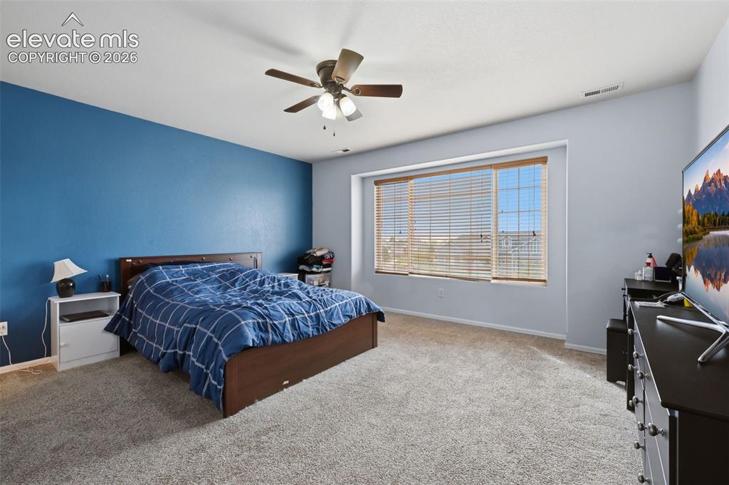 Image 18 of 21: Spacious room with plush carpeting, ceiling fan with integrated lighting, a