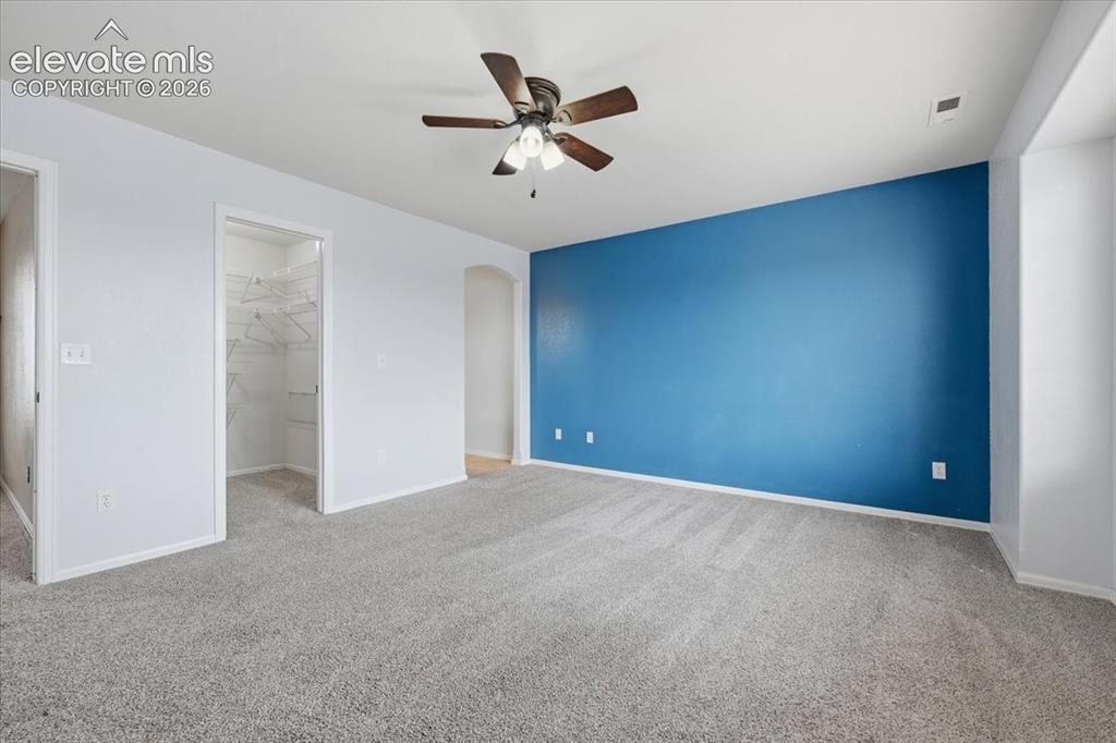 Image 18 of 26: Spacious room featuring plush carpet flooring, a ceiling fan, and a walk-in