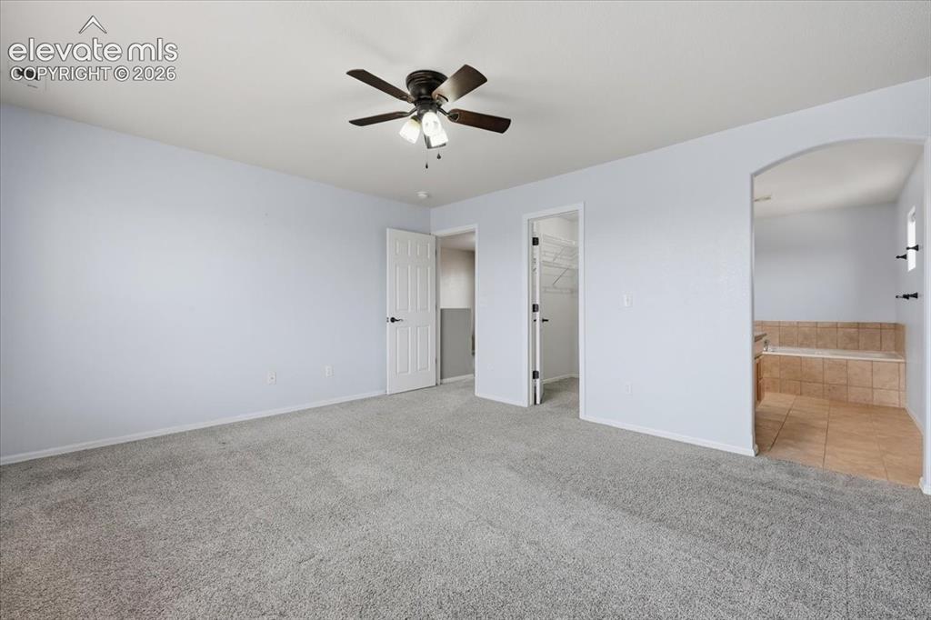 Image 19 of 26: Spacious interior with neutral carpeting, a ceiling fan, a walk-in closet,