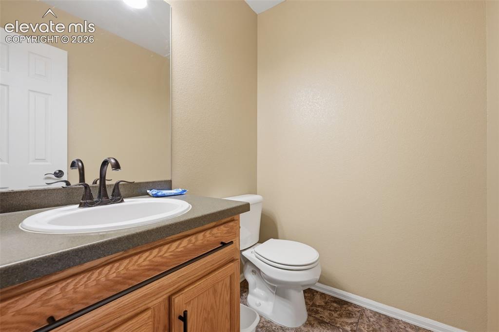 Image 20 of 21: Vanity with wood-finish cabinetry, solid surface countertop, and undermount