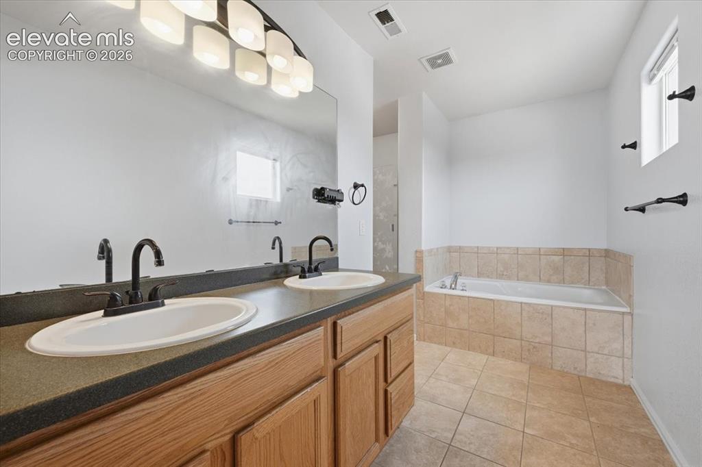 Image 20 of 26: Dual vanity with undermount sinks and black fixtures, expansive countertop