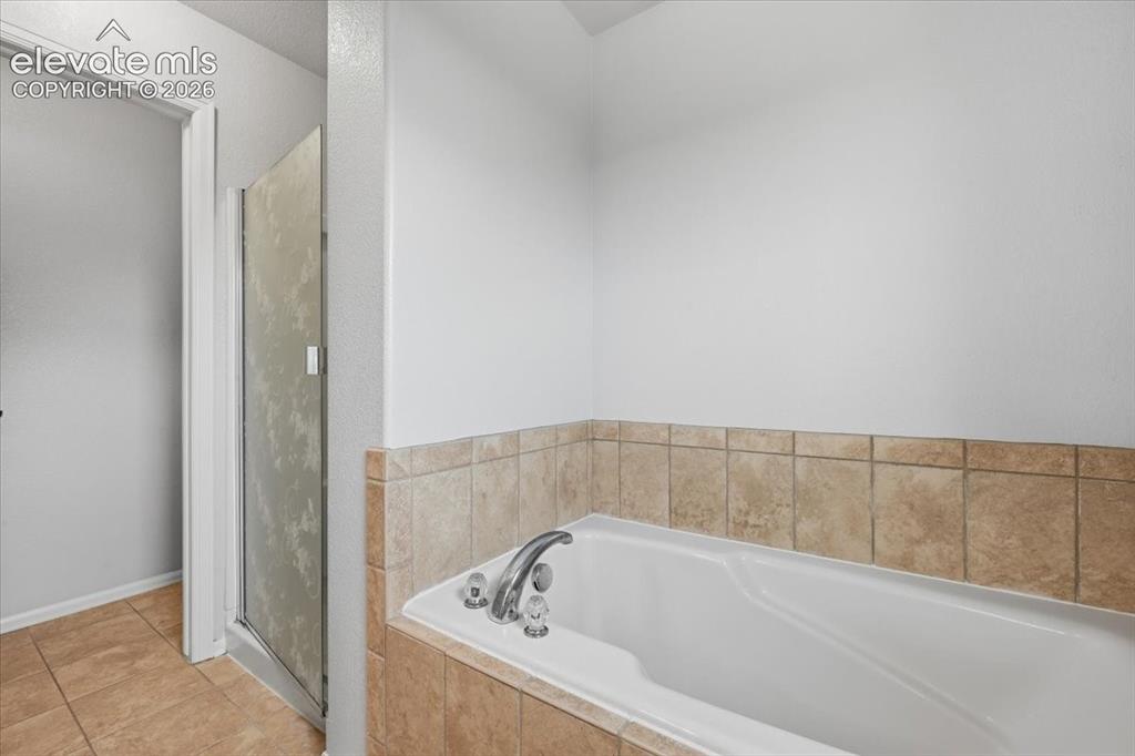 Image 21 of 26: Built-in soaking tub with chrome fixtures, surrounded by tiled decking and