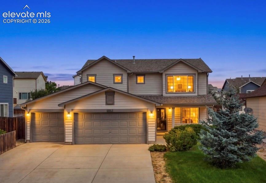 Image 3 of 21: Two-story residence featuring light-colored siding, a multi-car garage with