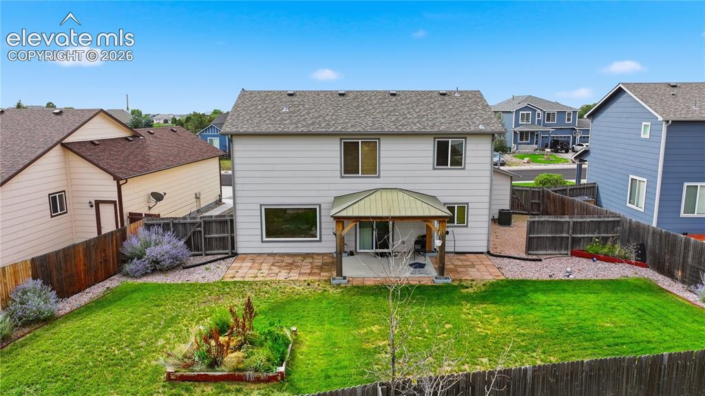 Image 4 of 21: Expansive backyard with a covered patio, paved patio area, green lawn, and 