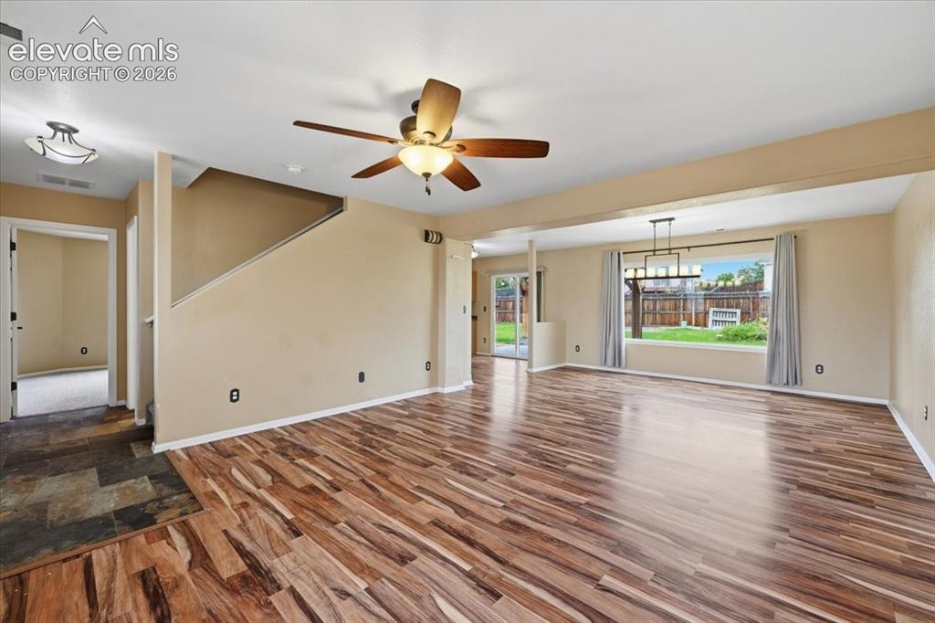 Image 5 of 26: Wood-finish flooring, ceiling fan, contemporary chandelier, large window wi
