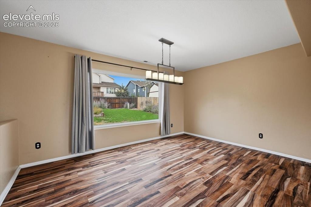 Image 8 of 26: Spacious room featuring wood-finish flooring, a large window, and a linear