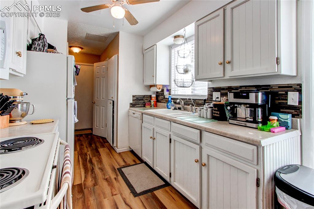 Image 10 of 36: Kitchen with sink, white cabinets, white appliances, and light wood-type fl