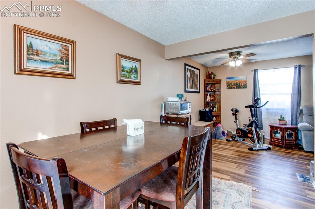 Image 12 of 36: Dining room with ceiling fan, wood-type flooring, and a textured ceiling