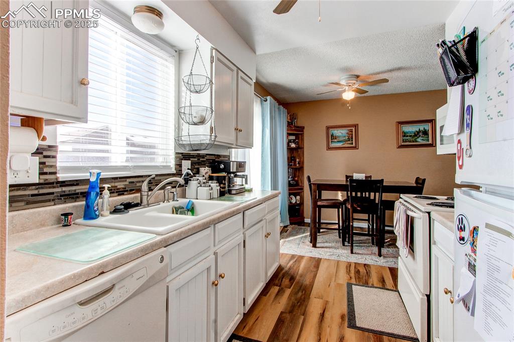 Image 8 of 36: Kitchen featuring sink, white cabinetry, a textured ceiling, white applianc