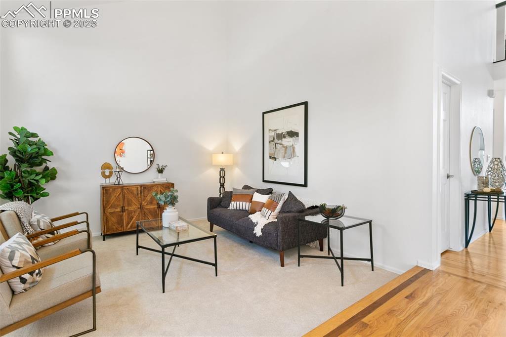 Image 10 of 50: Living room featuring a towering ceiling and light wood-style flooring