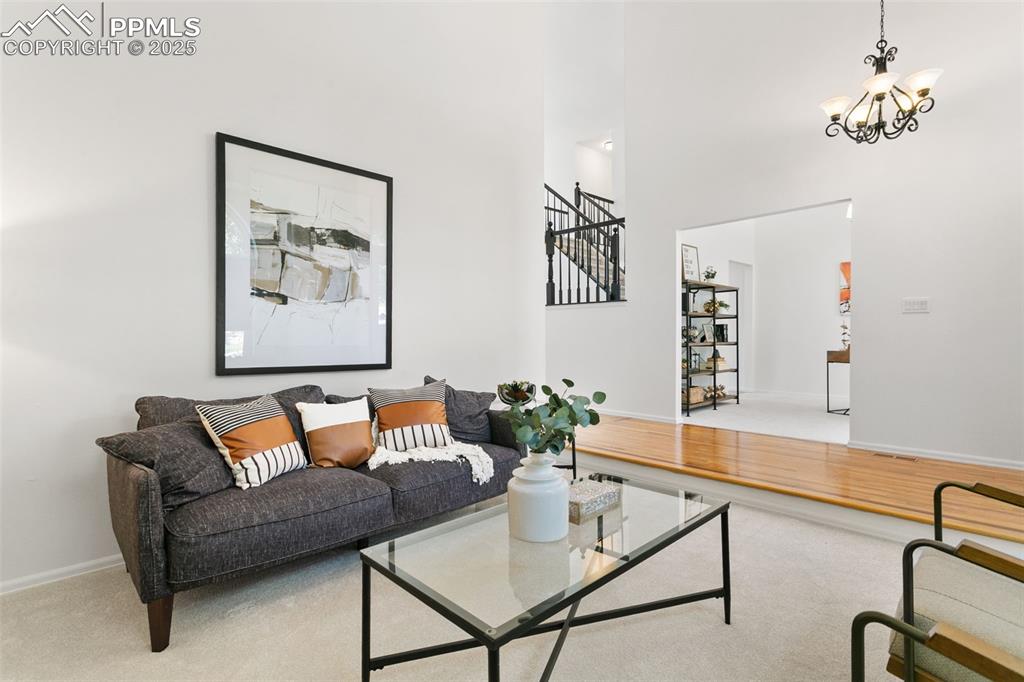 Image 12 of 50: Living room featuring a high ceiling, stairs, a chandelier, and carpet floo