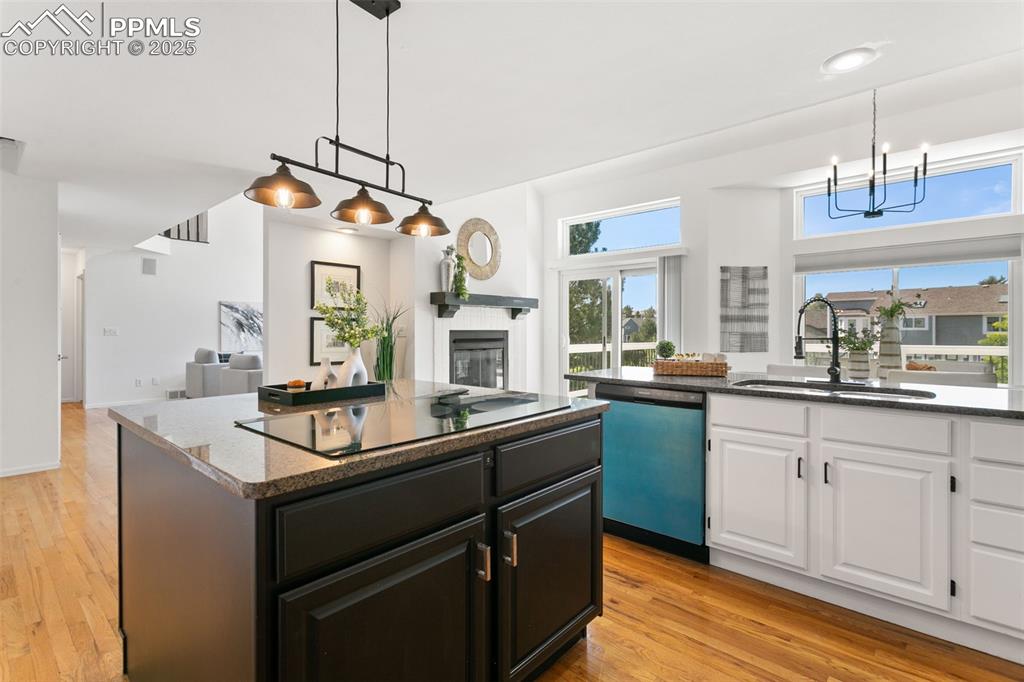 Image 14 of 50: Kitchen featuring light wood-type flooring, a glass covered fireplace, whit
