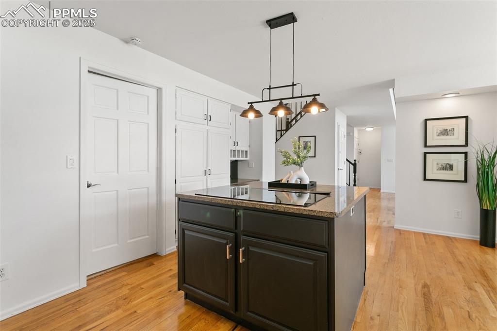 Image 15 of 50: Kitchen featuring light wood-style floors, a center island, dark stone coun