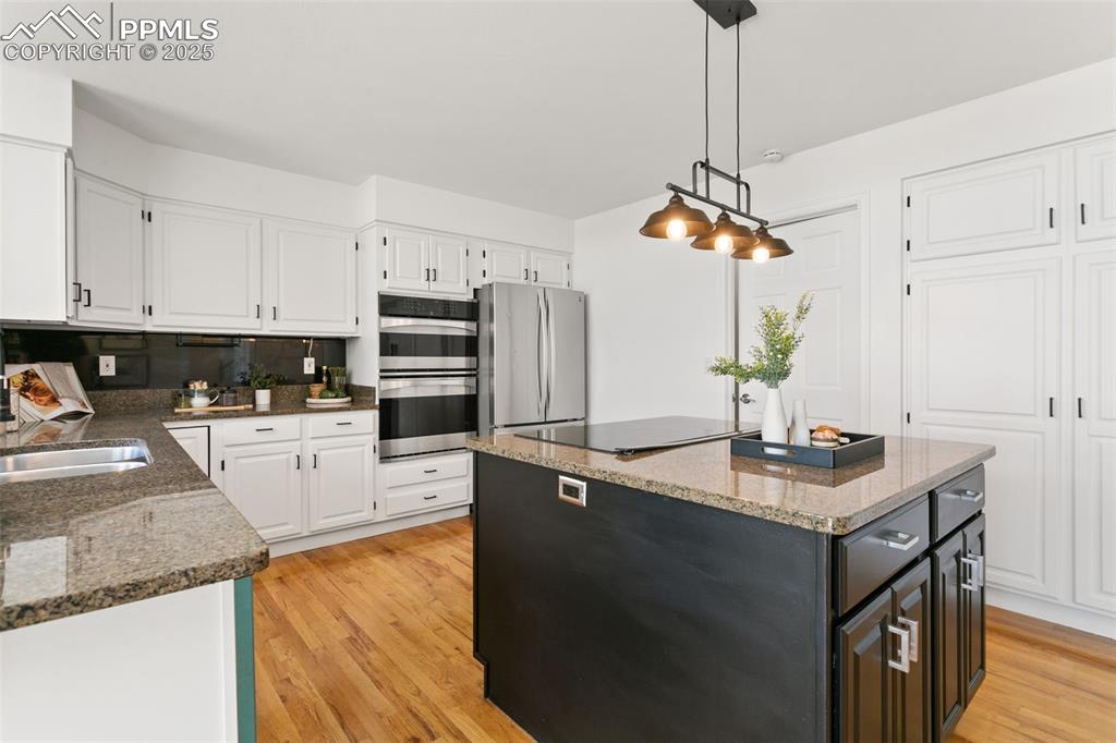 Image 16 of 50: Kitchen with white cabinetry, light wood-style floors, a center island, and