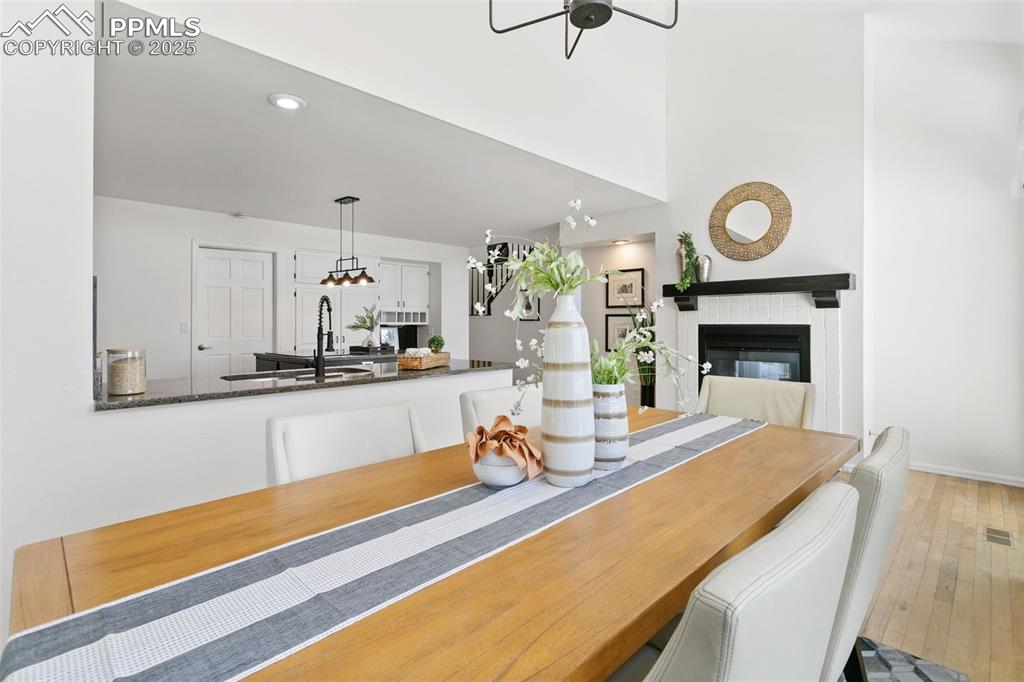 Image 19 of 50: Dining area with a fireplace, wood-type flooring, and recessed lighting