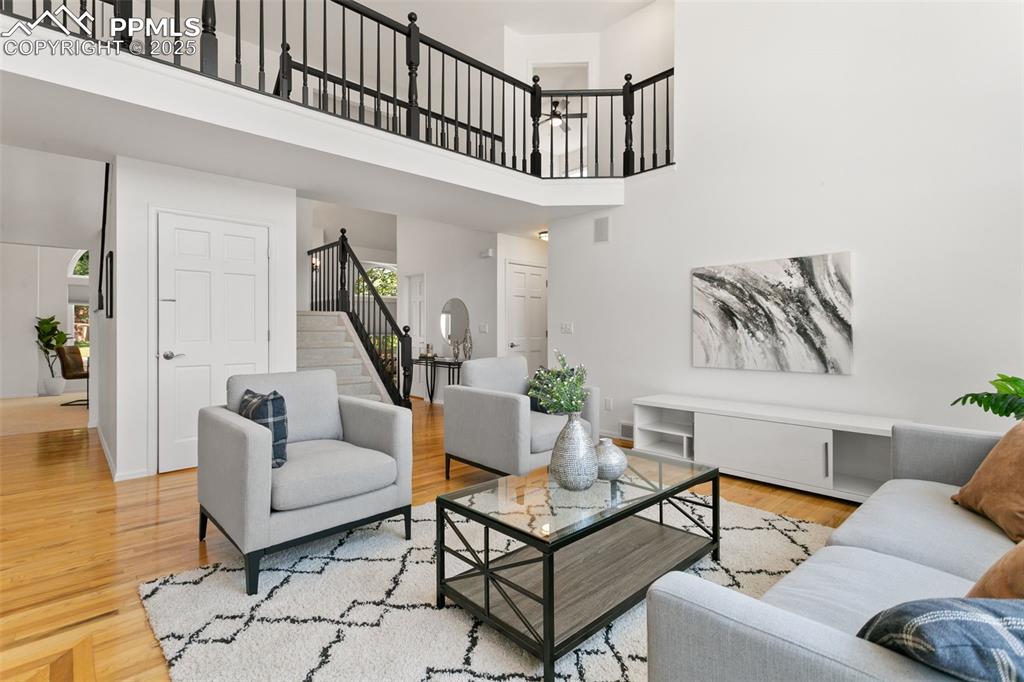 Image 21 of 50: Living room featuring a towering ceiling, wood finished floors, and stairs