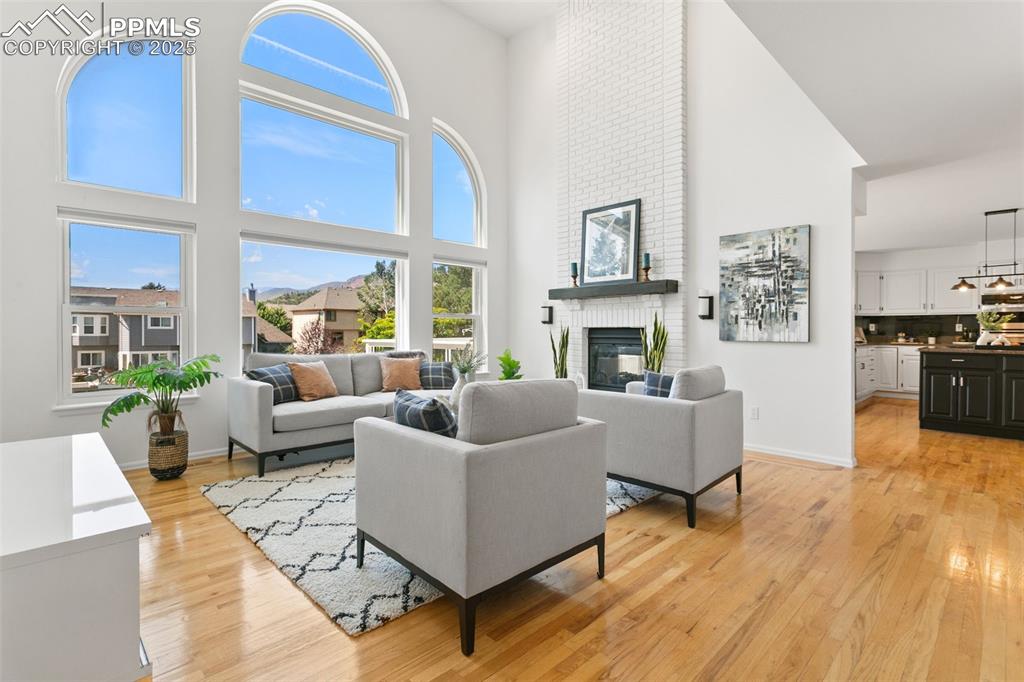 Image 22 of 50: Living area featuring a brick fireplace, light wood-type flooring, plenty o