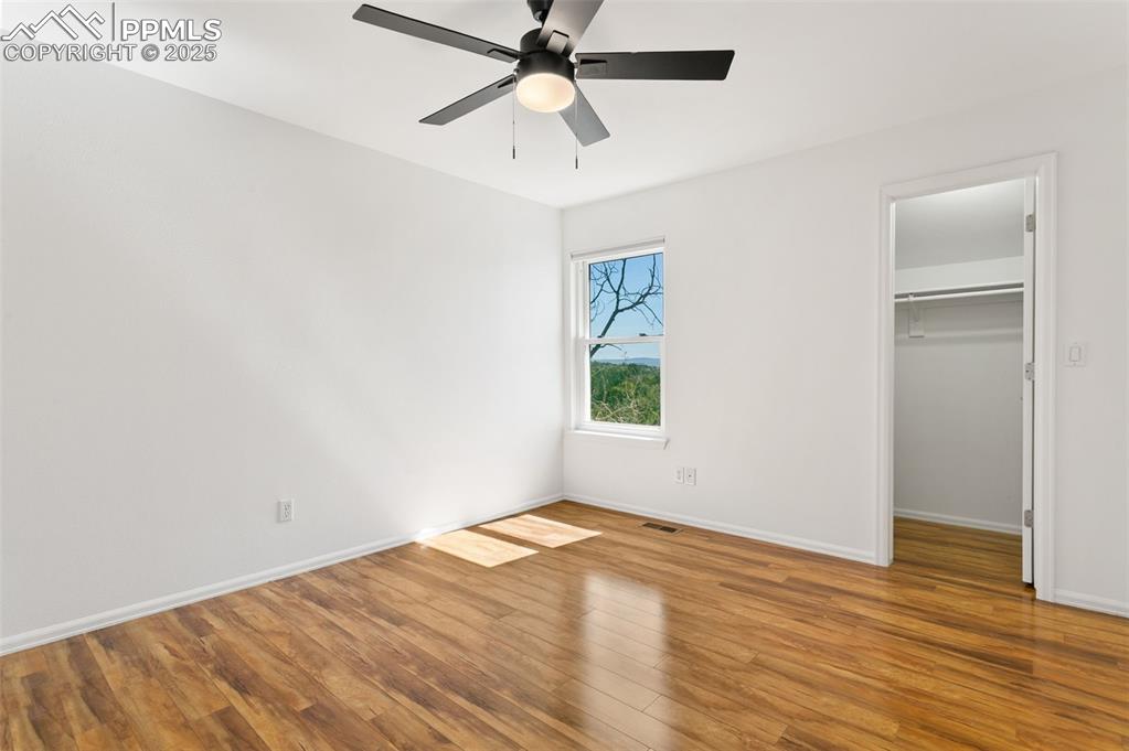 Image 28 of 50: Unfurnished bedroom with wood finished floors, a walk in closet, and ceilin