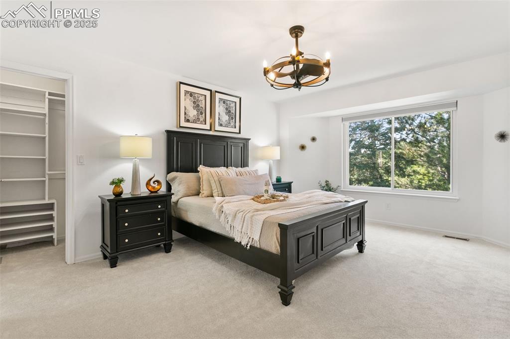 Image 31 of 50: Bedroom with light carpet, a spacious closet, and a chandelier