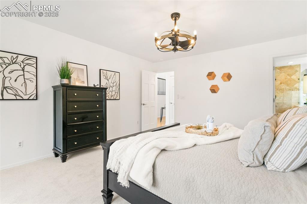 Image 33 of 50: Bedroom with light carpet and a chandelier