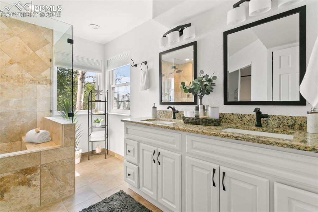 Image 34 of 50: Bathroom featuring double vanity, a tile shower, tile patterned floors, and