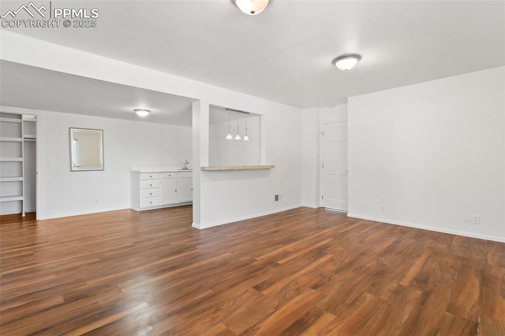 Image 40 of 50: Unfurnished living room featuring dark wood-style flooring and baseboards