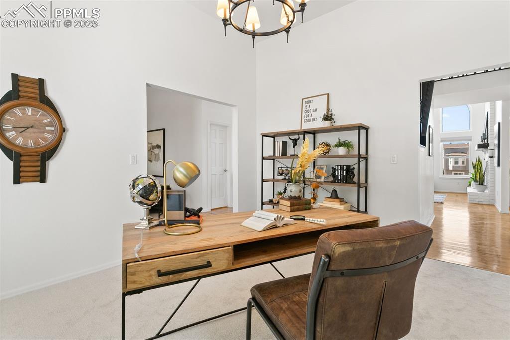 Image 9 of 50: Home office with a chandelier, carpet flooring, and a high ceiling